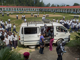  <p class='fr'>
	Des élèves regardent le véhicule amenant les femmes qui vont témoigner devant le tribunal installé dans l’amphithéâtre d’une école catholique à Minova.
	</p> <p class='en'>
	Students observing the van transporting women to testify in the courtroom set up in the auditorium of a local Catholic school in Minova.
	</p>